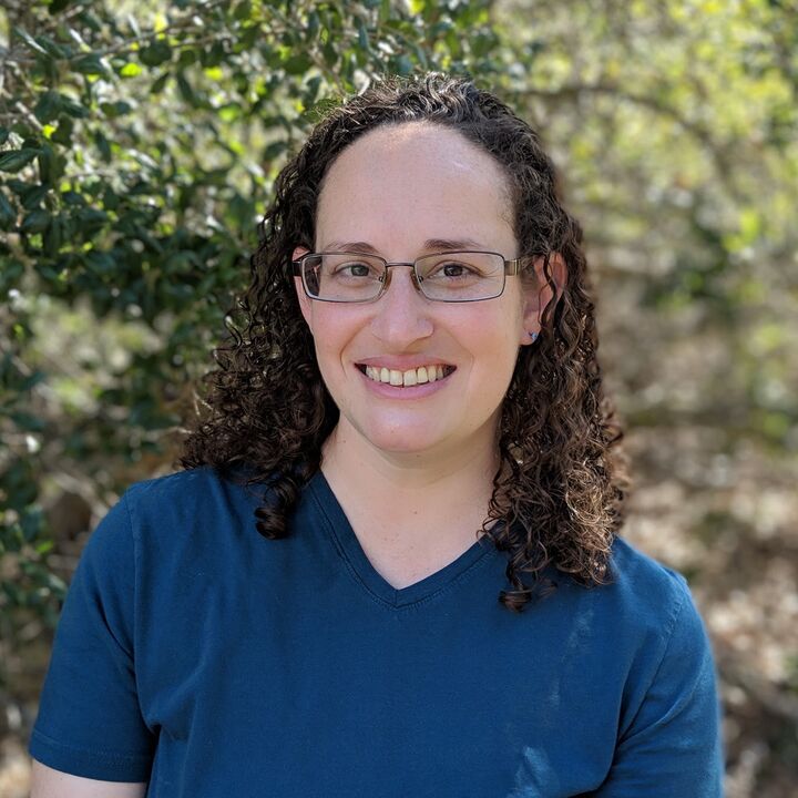 Ashley Dabbas, smiling, outdoors among green trees
